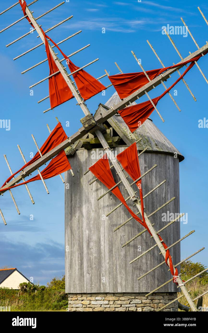 Tradizionale mulino a vento con vele rosse nella campagna della Bretagna, Francia, che rappresenta il patrimonio storico e il fascino rurale Foto Stock