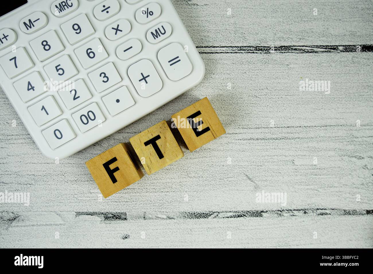 Testo FTE (Full Time Equivalent) con calcolatrice su sfondo in legno Foto Stock