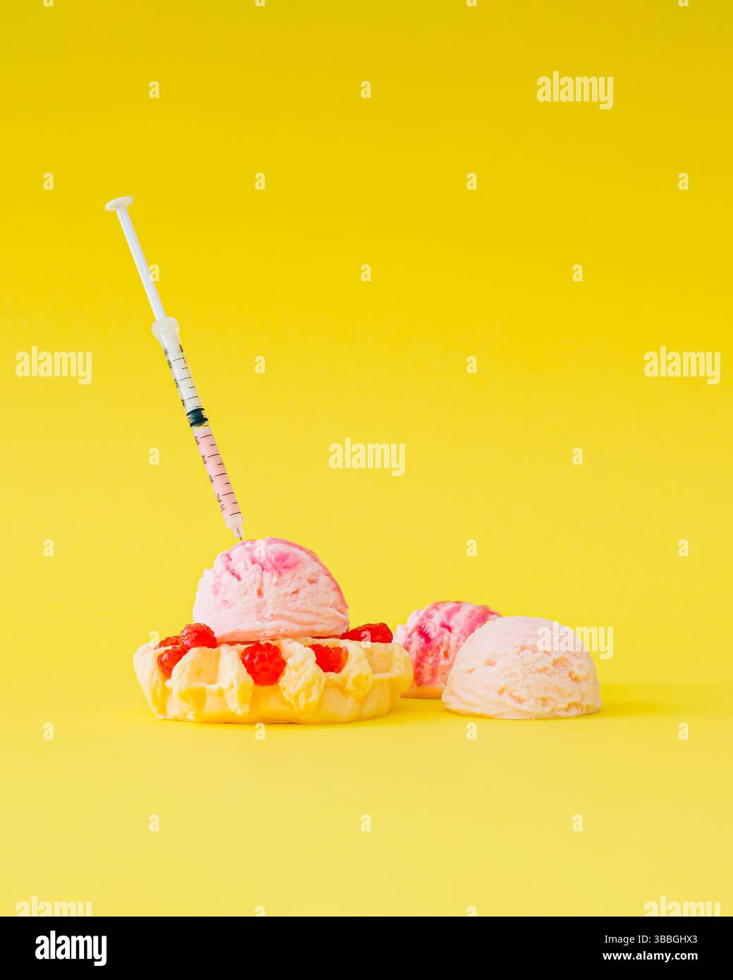 Siringa per iniettare liquido rosa in deliziosi waffle con lamponi e paletta per gelato su sfondo giallo brillante. Foto Stock