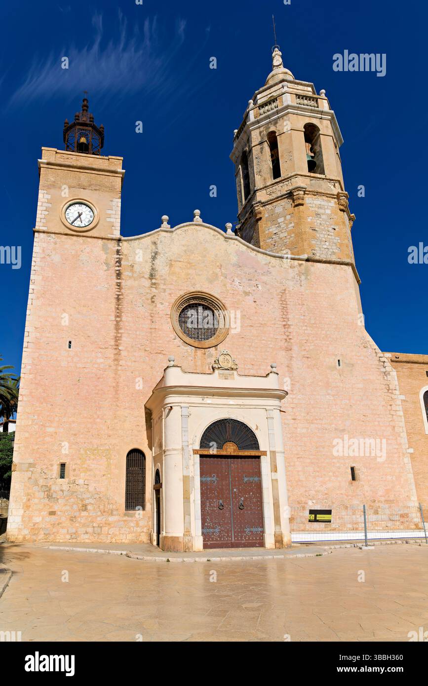 La chiesa di Sitges, in Spagna, si affaccia sul Mar Mediterraneo, con gente che cammina lungo il lungomare Foto Stock
