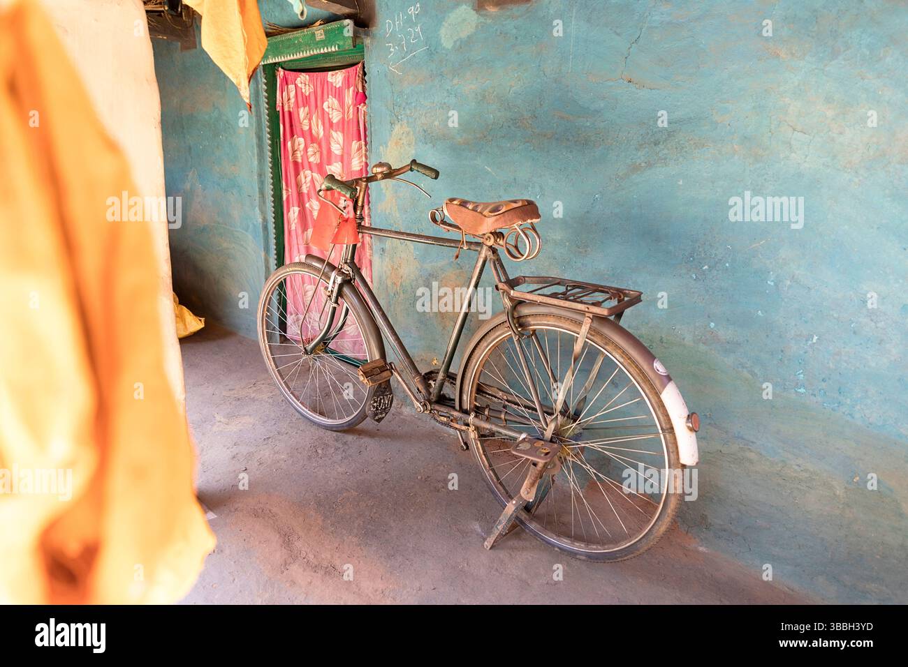 Vecchia bicicletta di fronte a una casa colorata fatta di fango in un piccolo villaggio nella parte rurale di orissa in india Foto Stock