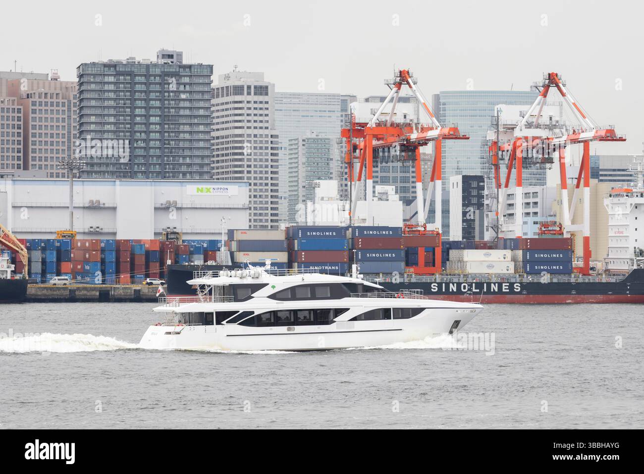 Una barca passa davanti a un molo di carico container nella baia di Tokyo. Il Giappone è fortemente dipendente dalle esportazioni (ad esempio, automobili, elettronica), affronta i rischi derivanti dalle tariffe statunitensi, in particolare sulle automobili (una tariffa proposta del 25% durante il primo mandato di Trump è stata rinviata, ma rimane una preoccupazione). Tariffe più elevate potrebbero ridurre l'accesso al mercato statunitense del Giappone, aumentare i prezzi al consumo e danneggiare la crescita del PIL. Tuttavia, l'allineamento strategico del Giappone con gli Stati Uniti e le esenzioni da alcune tariffe (tariffe dell'acciaio nel 2018) offrono un parziale sollievo. Il Giappone ha anche imperniato per diversificare il commercio attraverso accordi come il CPTPP e il RCEP, riducendo la dipendenza o Foto Stock