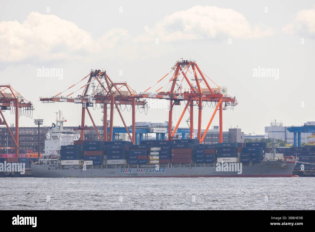 Una nave portacontainer completamente carica vista all'interno del porto di Tokyo. Il Giappone è fortemente dipendente dalle esportazioni (ad esempio, automobili, elettronica), affronta i rischi derivanti dalle tariffe statunitensi, in particolare sulle automobili (una tariffa proposta del 25% durante il primo mandato di Trump è stata rinviata, ma rimane una preoccupazione). Tariffe più elevate potrebbero ridurre l'accesso al mercato statunitense del Giappone, aumentare i prezzi al consumo e danneggiare la crescita del PIL. Tuttavia, l'allineamento strategico del Giappone con gli Stati Uniti e le esenzioni da alcune tariffe (tariffe dell'acciaio nel 2018) offrono un parziale sollievo. Il Giappone ha anche imperniato per diversificare il commercio attraverso accordi come il CPTPP e il RCEP, riducendo la dipendenza da Foto Stock