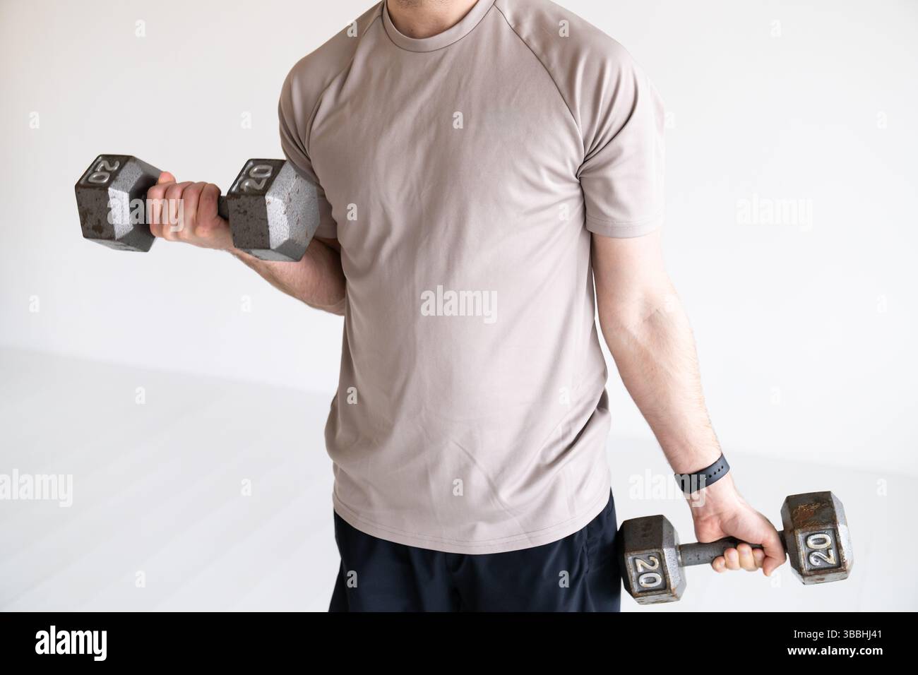 Uomo che solleva i manubri durante l'allenamento di forza Foto Stock