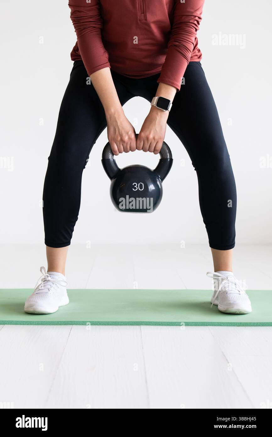 Donna che solleva Kettlebell durante l'allenamento di forza Foto Stock
