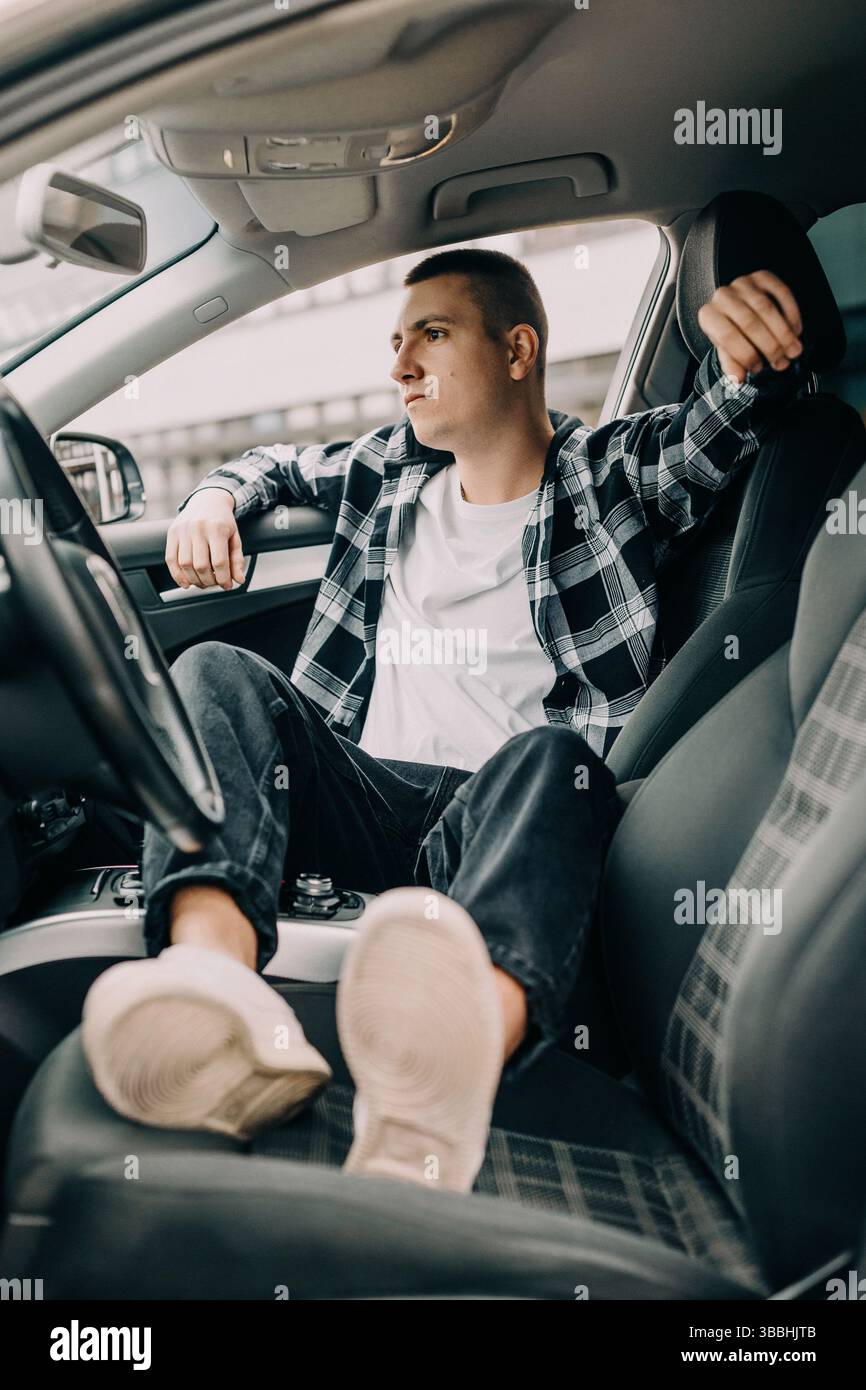 Giovane uomo rilassato seduto in auto umore premuroso Foto Stock