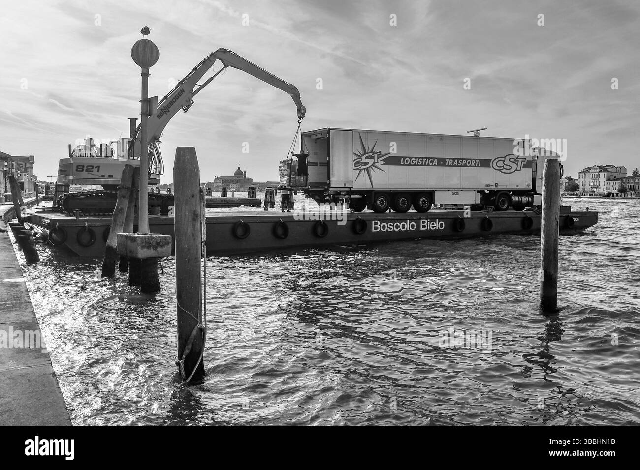 Bianco e nero. Chiatta ormeggiata alla fondamenta delle Zattere sul Canale della Giudecca, con una gru che carica merci su un camion, Venezia, Veneto, Italia Foto Stock