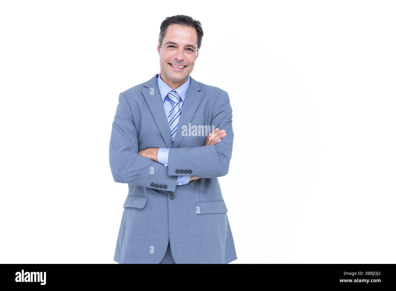 Un uomo di mezza età sorridente che incrocia le braccia sullo sfondo in studio, mostrando cravatta grigia a righe Foto Stock