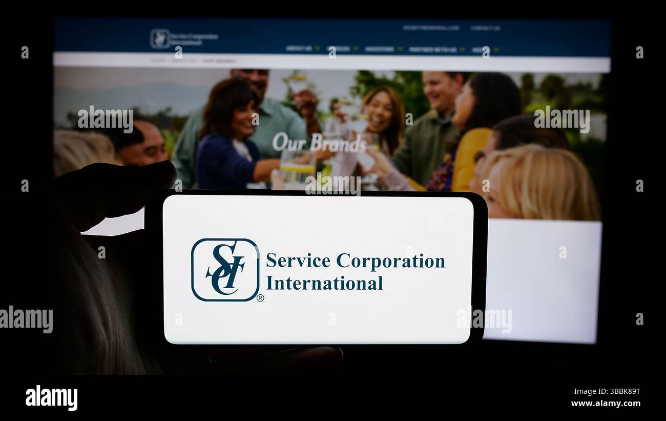 Stoccarda, Germania - 01-07-2024: Persona che tiene il cellulare con il logo della società funebre statunitense Service Corporation International sullo schermo Foto Stock