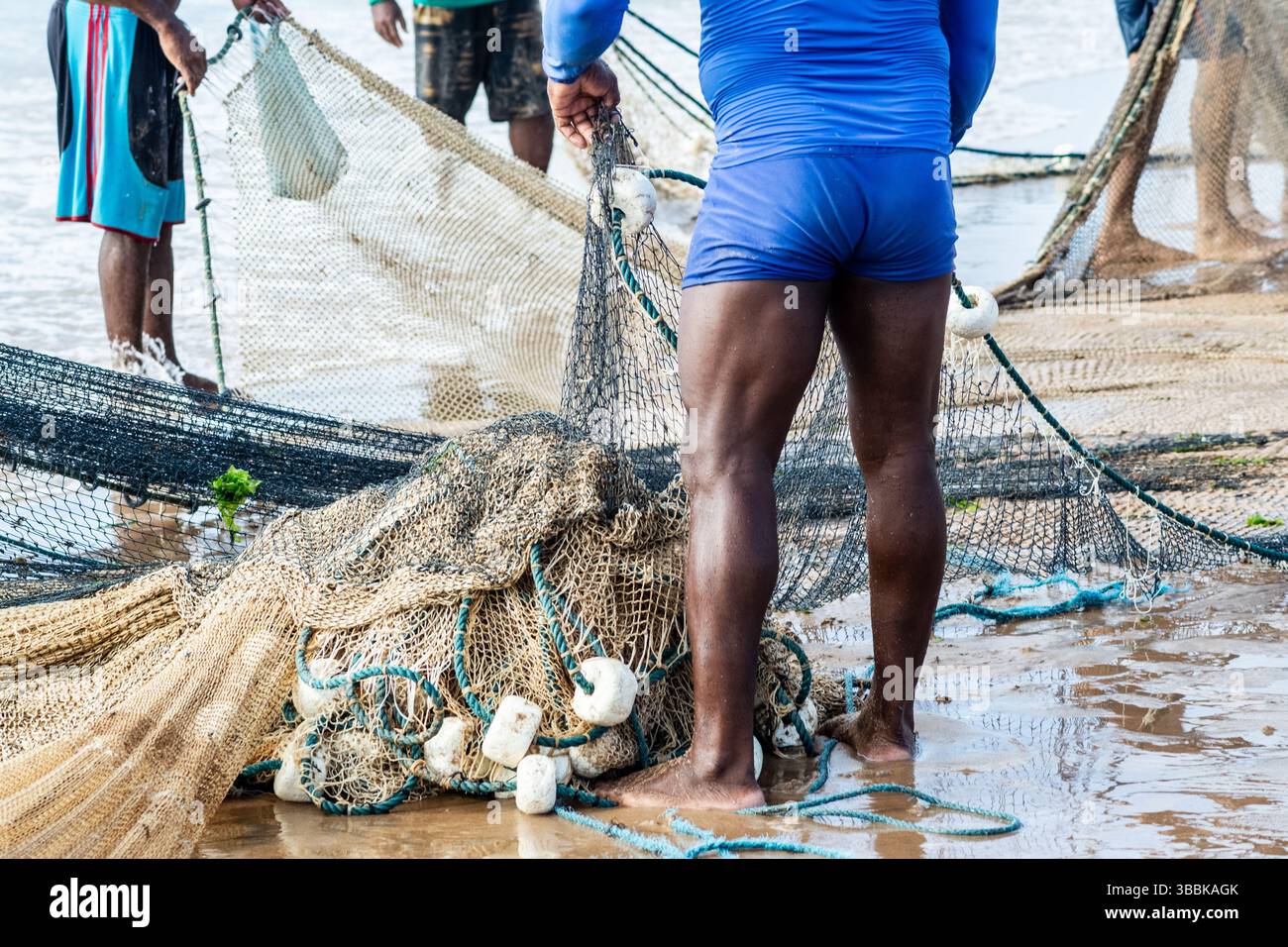 Mezzo corpo di pescatori non identificati che raccolgono la rete da pesca dopo la cattura del pesce. Pesce, pesca come hobby. Brasile Foto Stock
