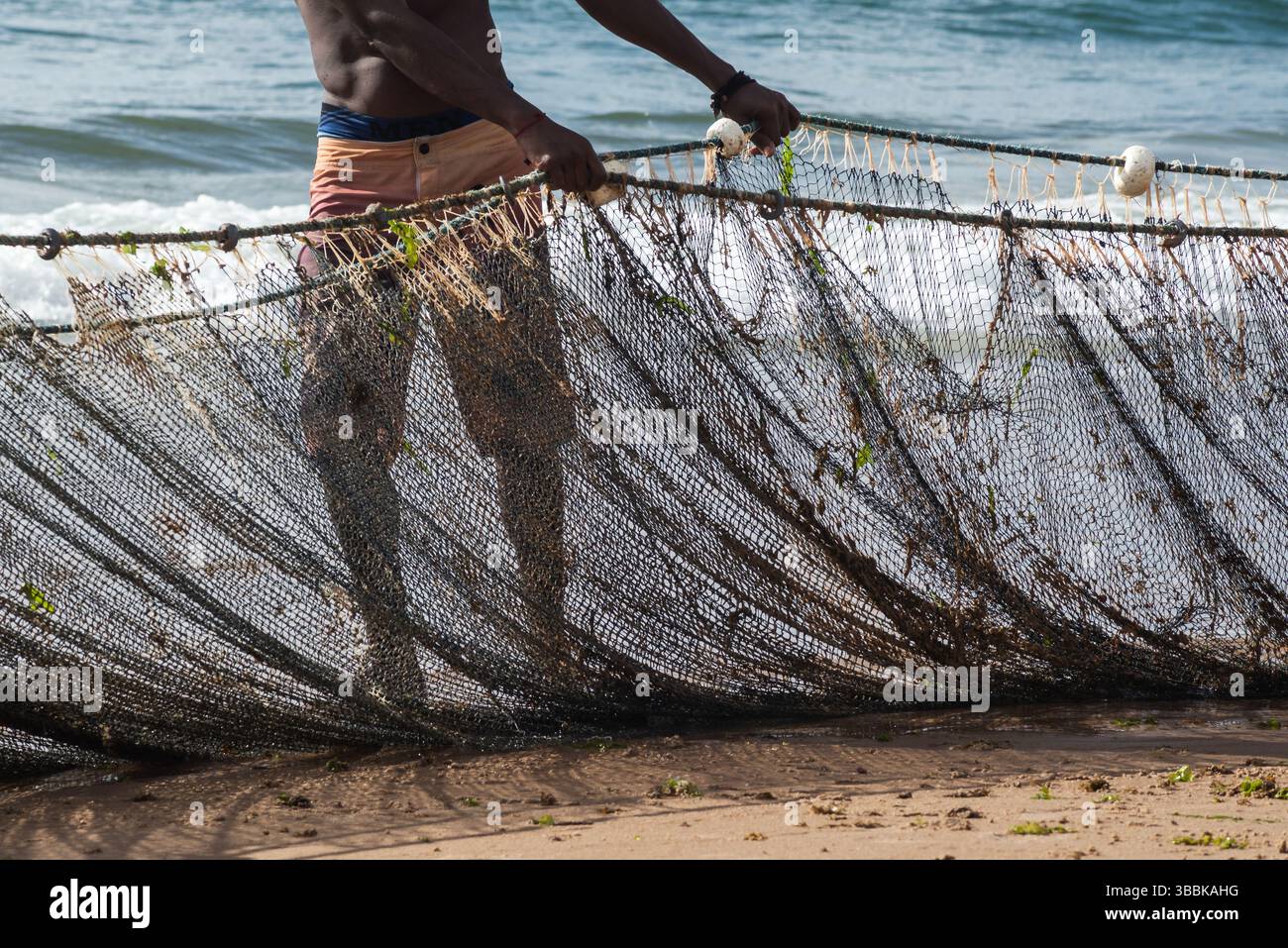 Mezzo corpo di un pescatore non identificato che tira una rete da pesca. specialità di pesce, hobby. Brasile Foto Stock