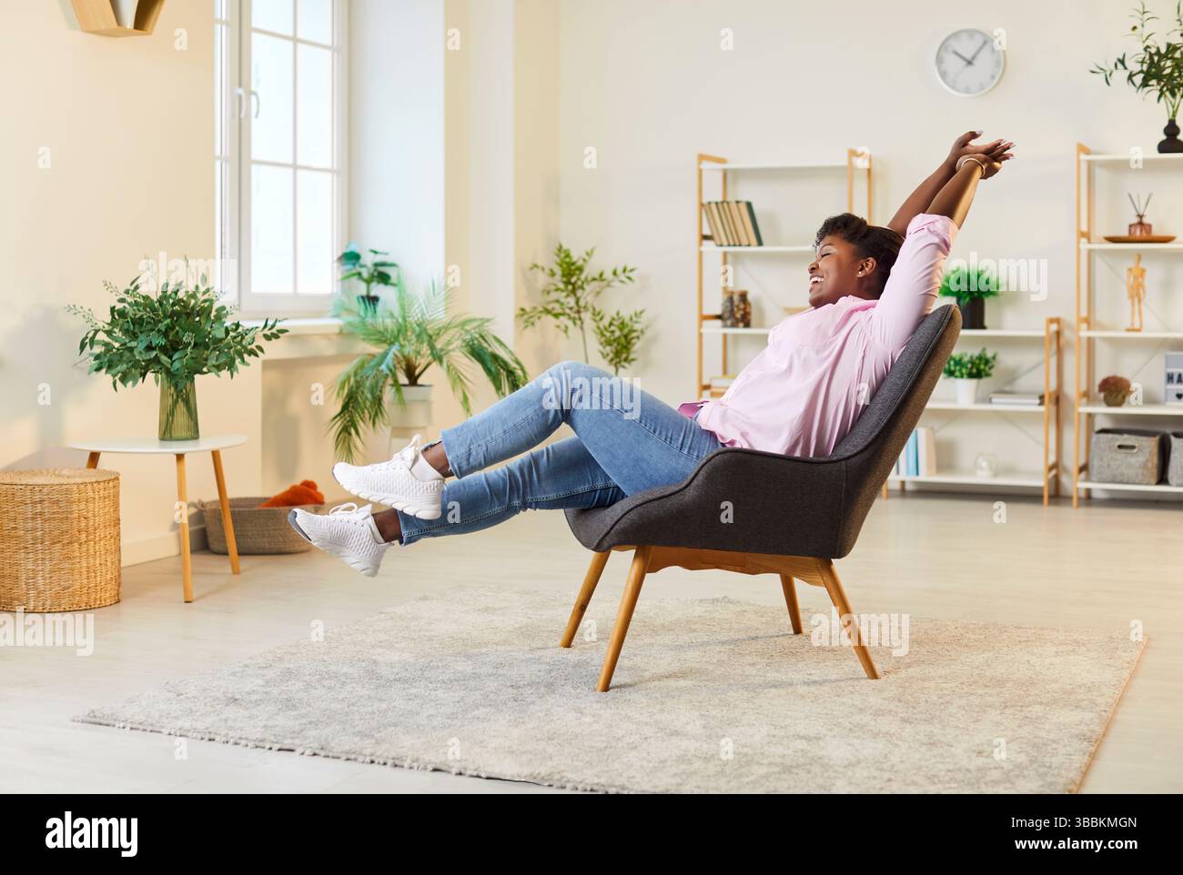 Felice donna afroamericana che si rilassa in poltrona e si allunga Foto Stock