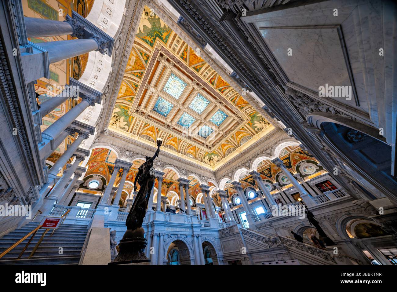 WASHINGTON DC - la grande sala del Thomas Jefferson Building presso la Library of Congress presenta una monumentale scalinata in marmo fiancheggiata da figure femminili in bronzo con braccia sollevate che tengono elettroliti simili a una torcia. Create dallo scultore Philip Martiny negli anni '1890, queste statue allegoriche servono sia come elementi decorativi che come luci funzionali all'interno degli ornati interni Beaux-Arts. La sala grande, completata nel 1897, presenta elaborate colonne in marmo, ornamenti dorati, pavimenti a mosaico e un soffitto a cassettoni adornato con lucernari placcati in rame, che esemplificano il Rinascimento americano Foto Stock