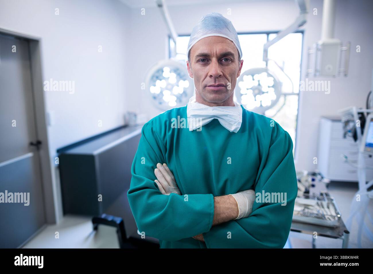 Chirurgo in piedi che indossa un elastico in sala operatoria, con lampada chirurgica e strumenti Foto Stock