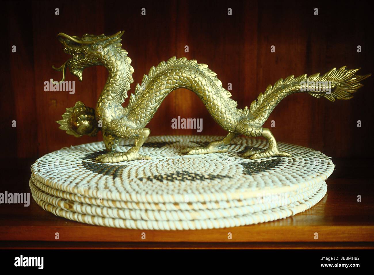 Una scultura di drago dorato in metallo su tappeto intrecciato Foto Stock