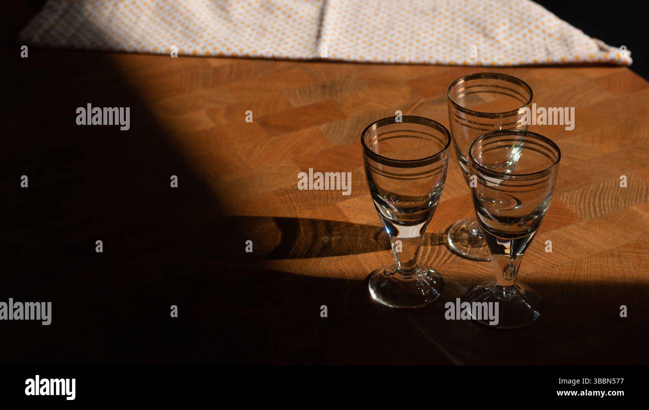 Tre shot di vodka su un tavolo di legno con tovagliolo alla luce del sole Foto Stock