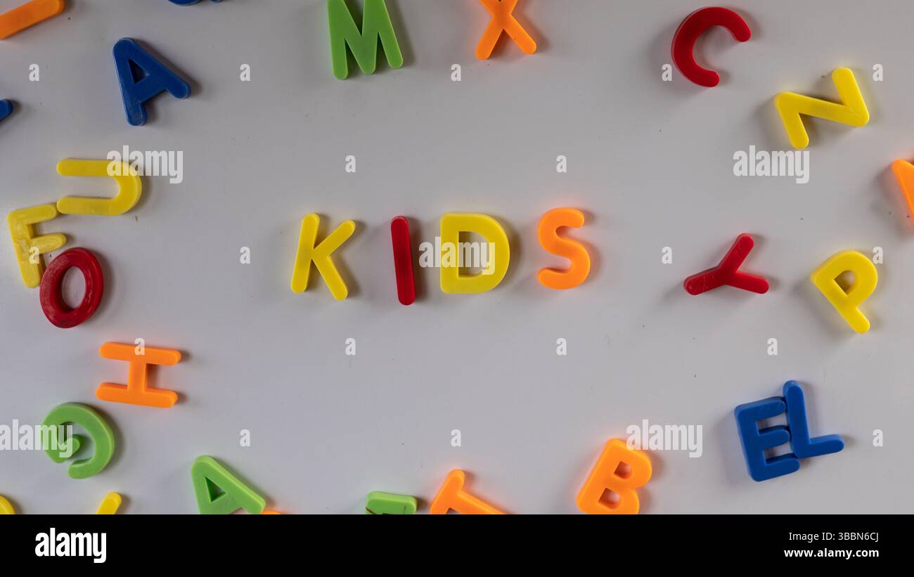 Lettere magnetiche colorate "bambini" su una lavagna in legno in aula o in sala giochi. Foto Stock