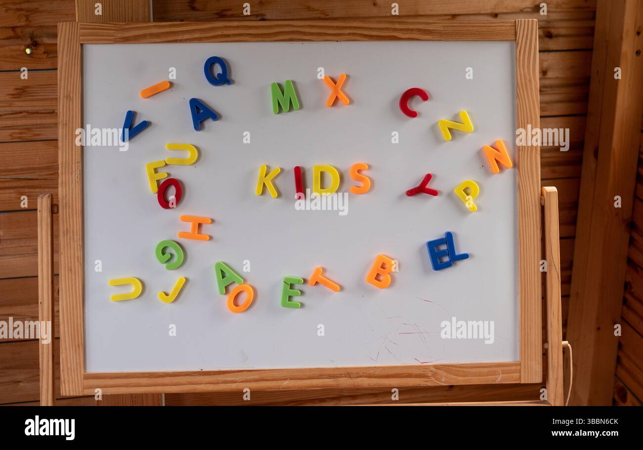 Lettere magnetiche colorate "bambini" su una lavagna in legno in aula o in sala giochi. Foto Stock