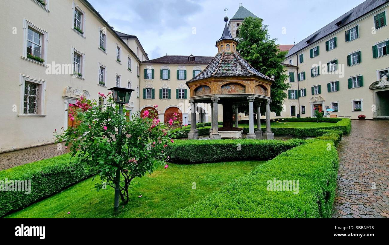 Pittoresco cortile dell'abbazia medievale di Novacella con l'antico pozzo coperto di miracoli costruito durante il Rinascimento in alto Adige, Italia Foto Stock