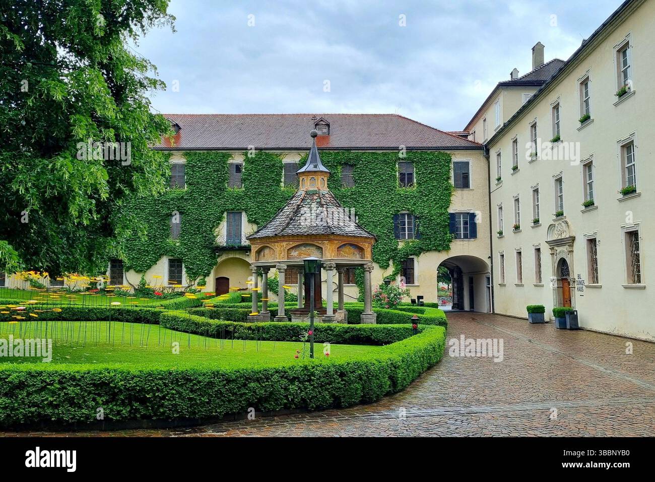 Il gazebo nel cortile dell'Abbazia di Novacella con un muro coperto di edera sullo sfondo Foto Stock