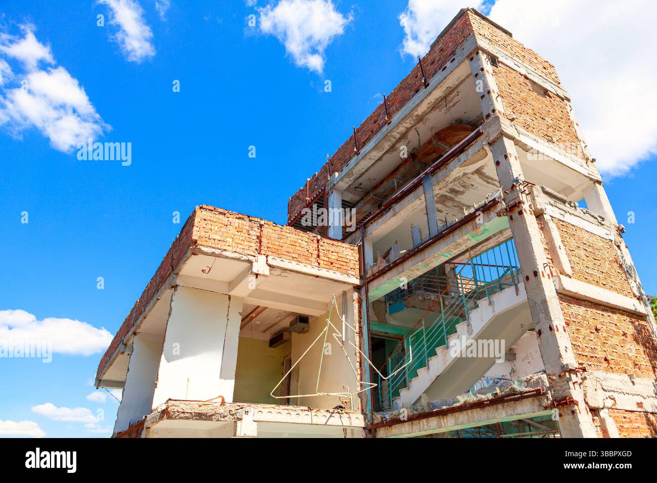 Edificio fatiscente, la sua struttura esposta contro il cielo. Demolizione in corso con travi in cemento e acciaio a vista. Struttura decadente dell'edificio Foto Stock