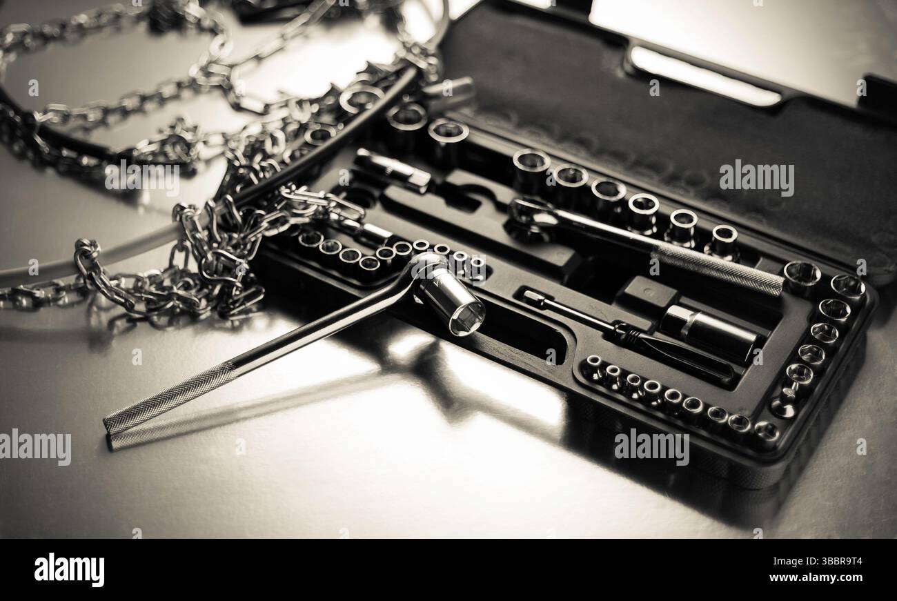 Set di chiavi a bussola cromate con catene in metallo su una superficie riflettente, che mostra stile industriale, precisione meccanica e gli elementi essenziali per l'officina. Foto Stock