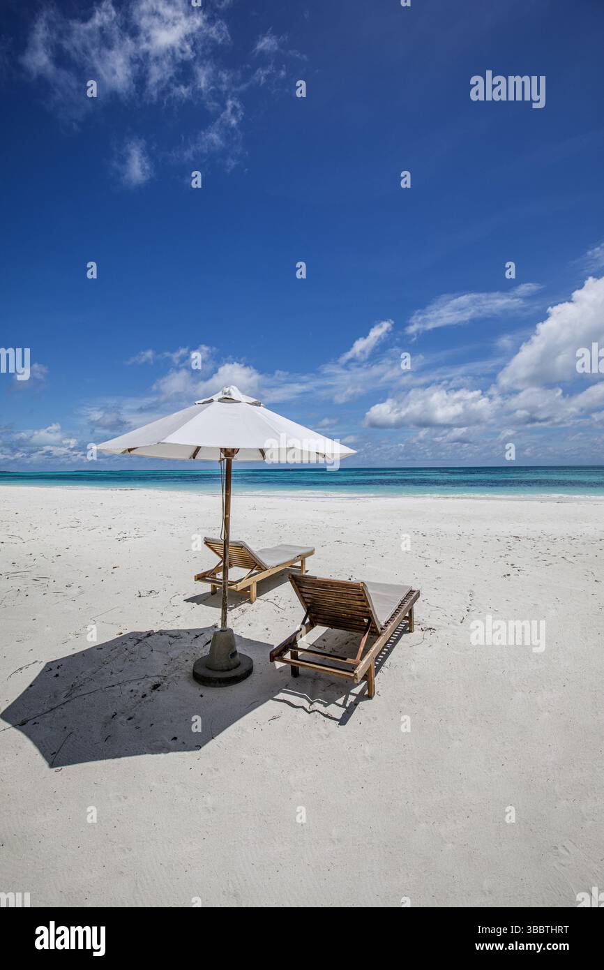 Spiaggia tropicale con sedie luminose e ombrelloni sulla spiaggia sabbiosa dell'isola paradisiaca, perfetta per vacanze di piacere e relax Foto Stock