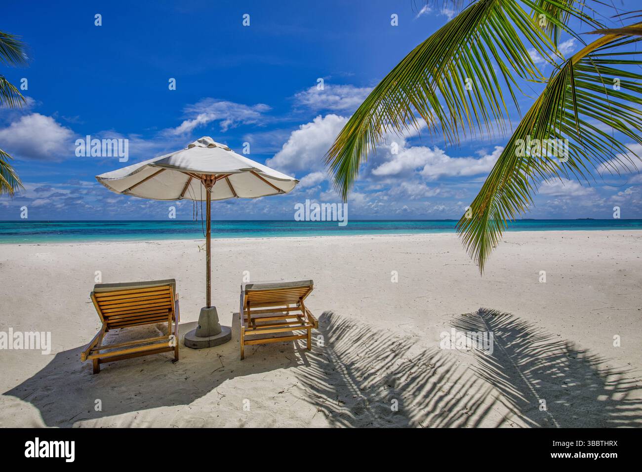 Spiaggia tropicale con sedie luminose e ombrelloni sulla spiaggia sabbiosa dell'isola paradisiaca, perfetta per vacanze di piacere e relax Foto Stock