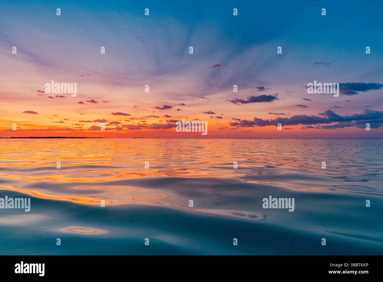 Tramonto con superficie d'acqua calma cielo sereno nuvole morbide che ispirano un'atmosfera tranquilla meditazione scena naturale relax paesaggio oceanico Foto Stock