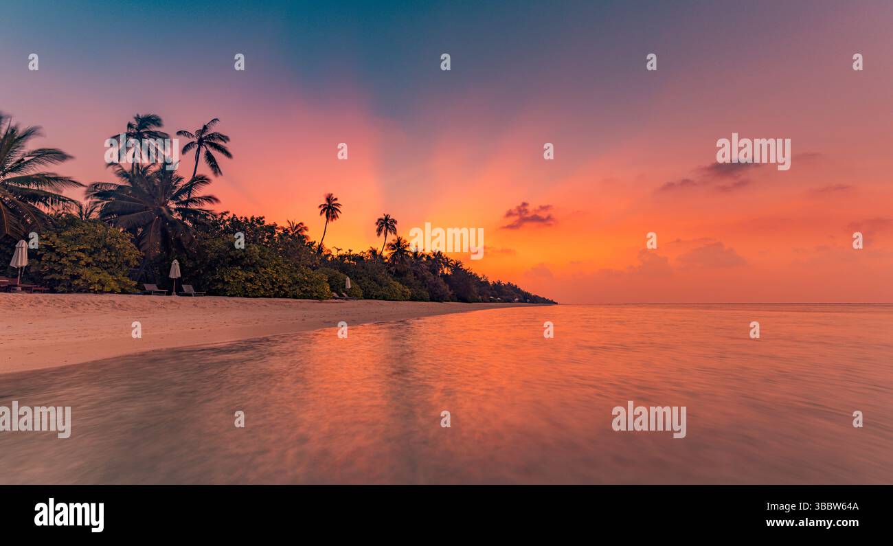 Pittoresco tramonto panoramico sulla costa tropicale dell'isola con mare, sabbia, laguna e cielo, suggestivo paesaggio paradisiaco bagnato dalla luce dorata del sole Foto Stock