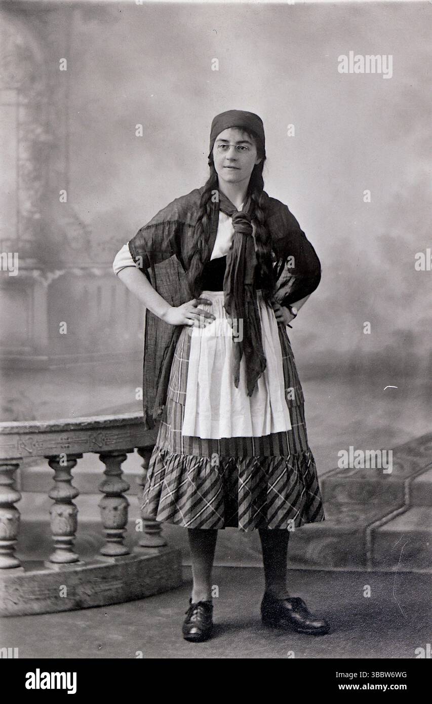 Una donna in abiti da lavoro, molto probabilmente per uno spettacolo teatrale. Indossa una gonna a motivi geometrici con un grembiule, una sciarpa, uno scialle e un cappello. Originariamente fotografato da Horace Dudley che era attivo come fotografo nei primi anni '1900 Secondo il Kelly's Directory del 1913, operò al 259A High Street, Lincoln. Da una collezione mista di cartoline edoardiane. Foto Stock