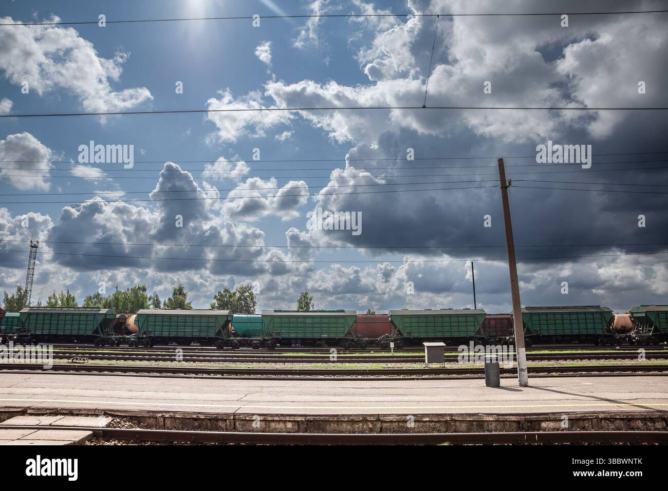 Una linea di carri tramogge verdi e rossi arrugginiti carichi di grano russo si trova sui binari del cantiere sotto enfatizza il corridoio merci baltico, proveniente dalla russia, o Foto Stock