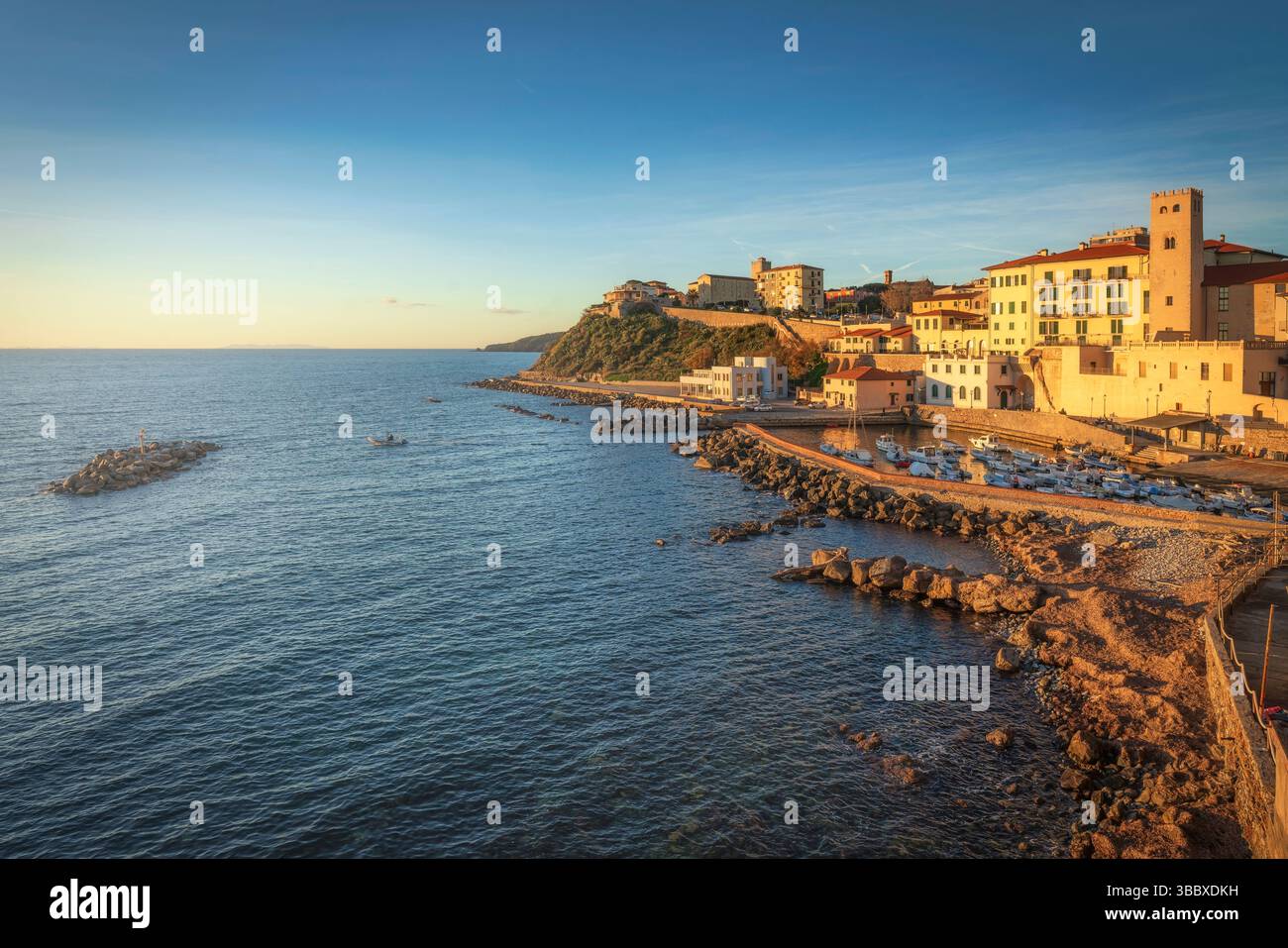 Tramonto sul lungomare di Piombino e barche nel porticciolo. Seascape in Maremma, Toscana, Italia Foto Stock