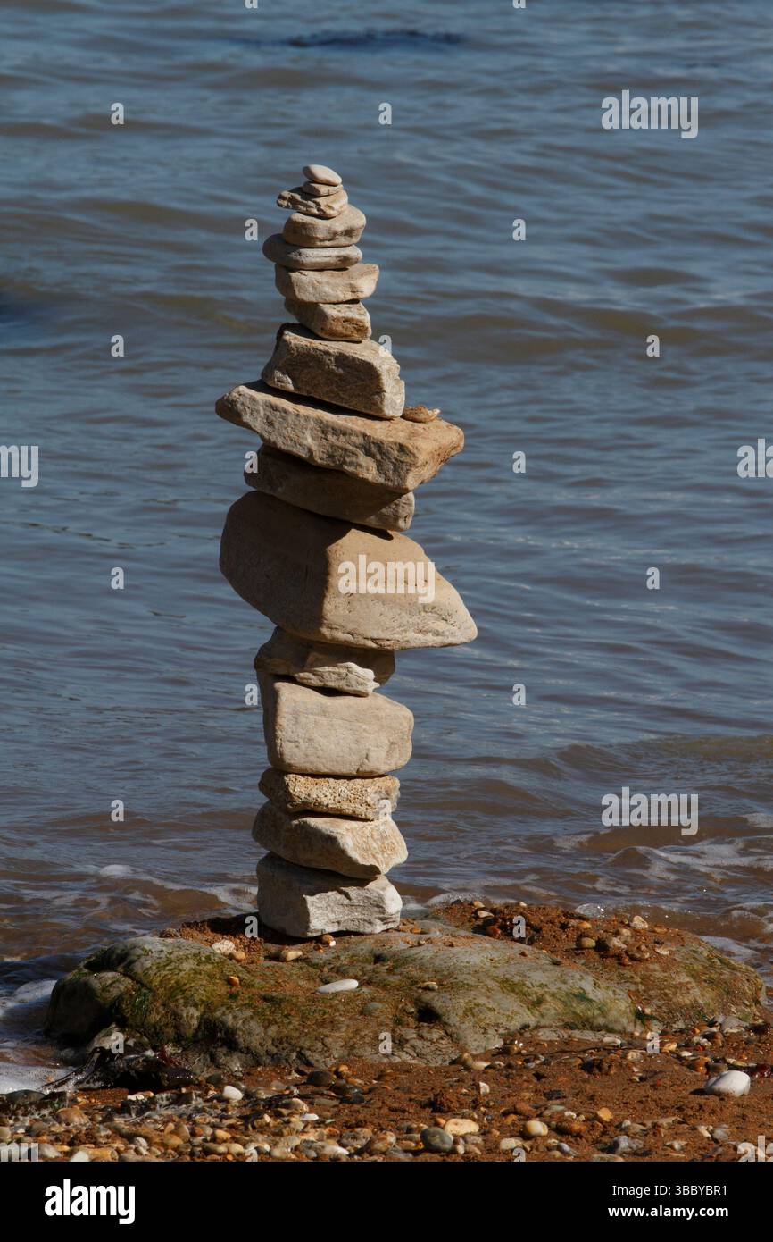 Cairn su una spiaggia con la marea in arrivo. Foto Stock