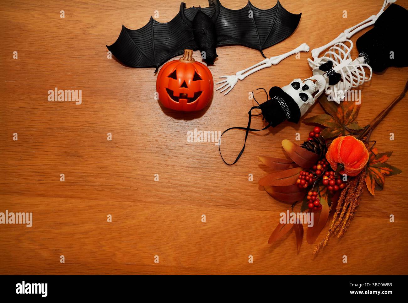 Un appartamento natalizio di Halloween è caratterizzato da una lanterna jack-o'-lanterna, pipistrello nero, scheletro con cappello e decorazioni a tema autunnale, tra cui frutti di bosco e foglie Foto Stock