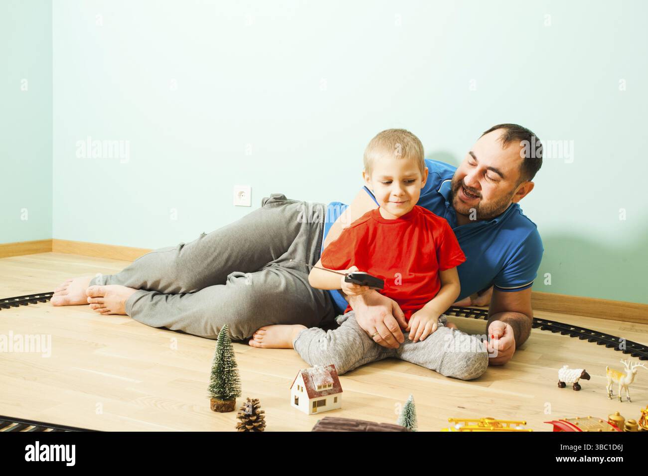 Ragazzo e padre giocano con il suo treno in camera. Tempo in famiglia con i bambini Foto Stock