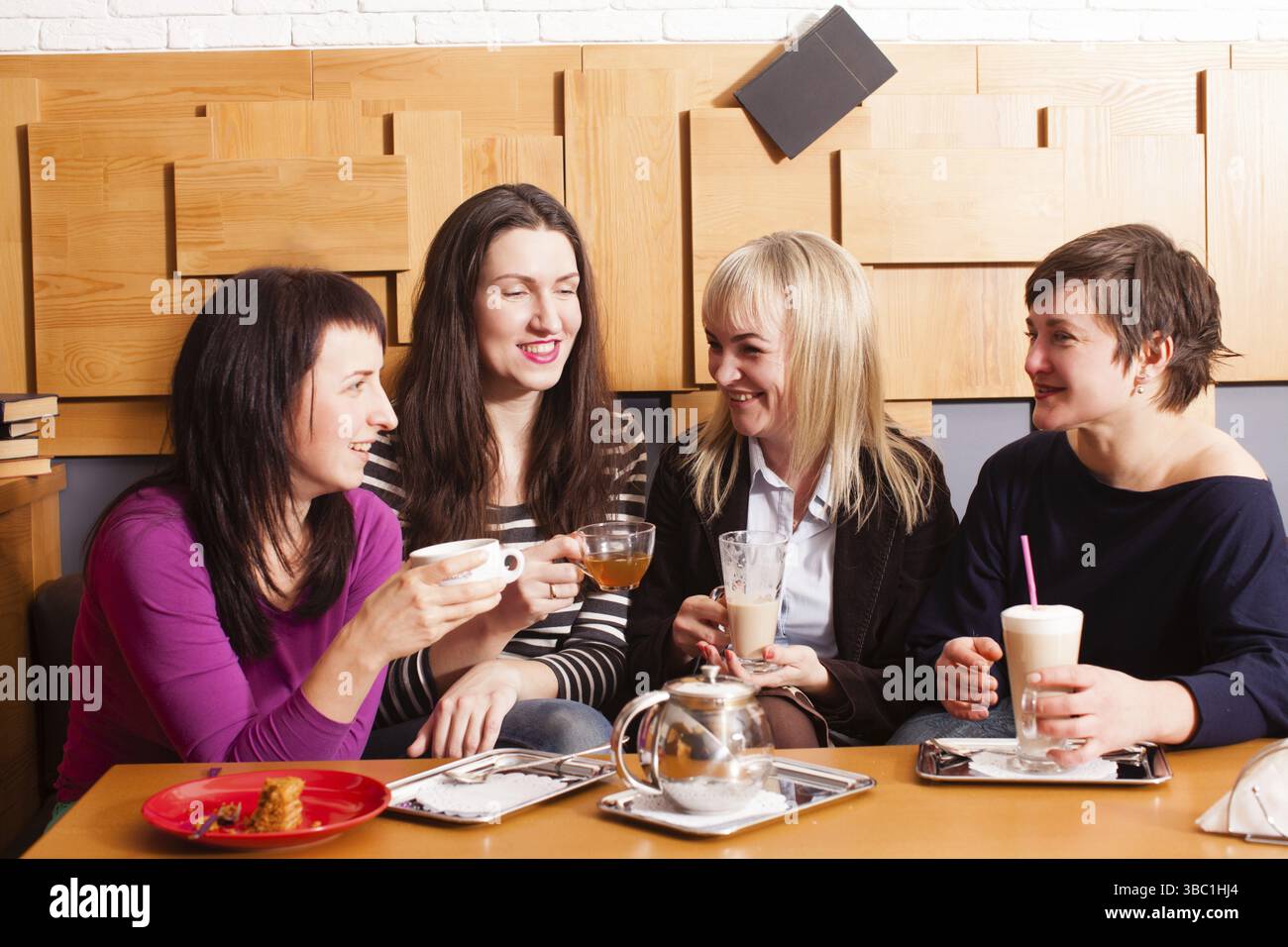 Amiche a discutere le ultime notizie durante la riunione informale nella caffetteria Foto Stock