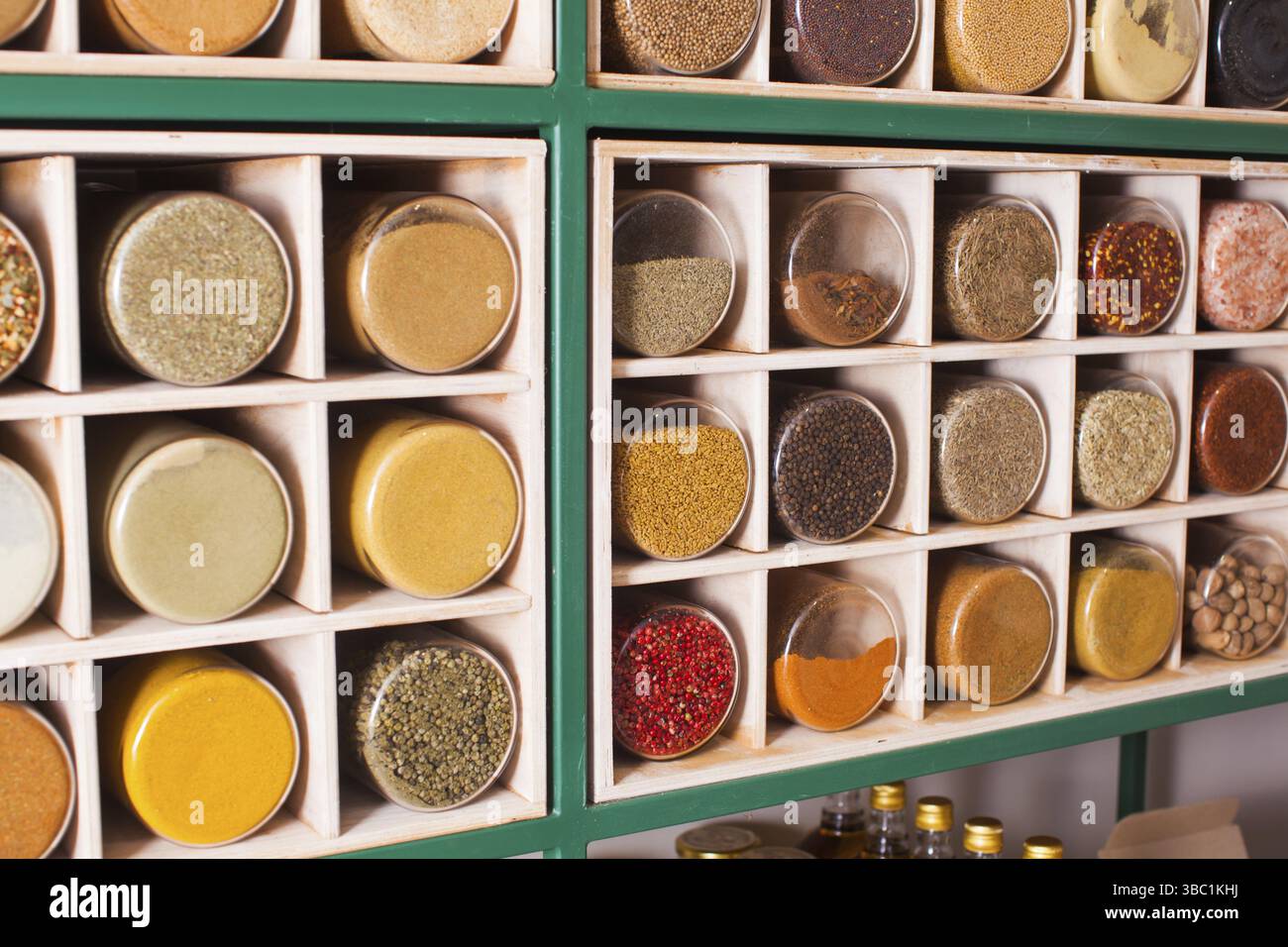 Collezione di vasi di vetro riempiti con alcune spezie in polvere in piedi su un vecchio stand di legno. Varietà di erbe e spezie in polvere su una griglia Foto Stock