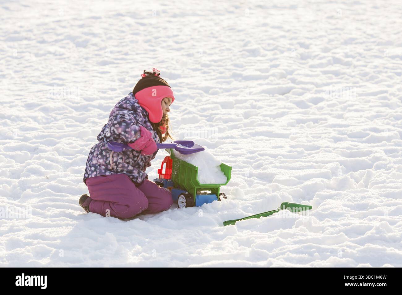 Il bambino gioca con l'auto e la pala. Concetto di pulizia della neve in città Foto Stock