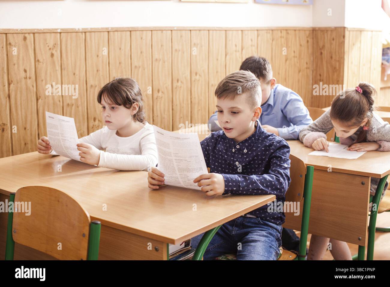 I bambini della scuola primaria che prendono un test della scuola di scrittura dell'esame Foto Stock