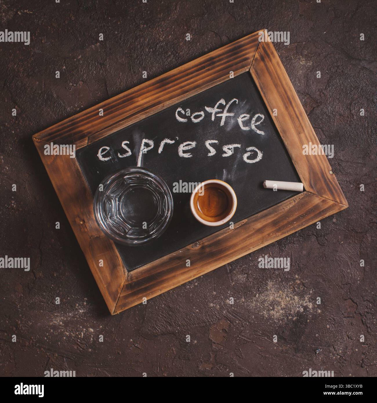 Vista dall'alto di una tazza di caffè e acqua in vetro su una vecchia scuola ardesia con iscrizione Foto Stock