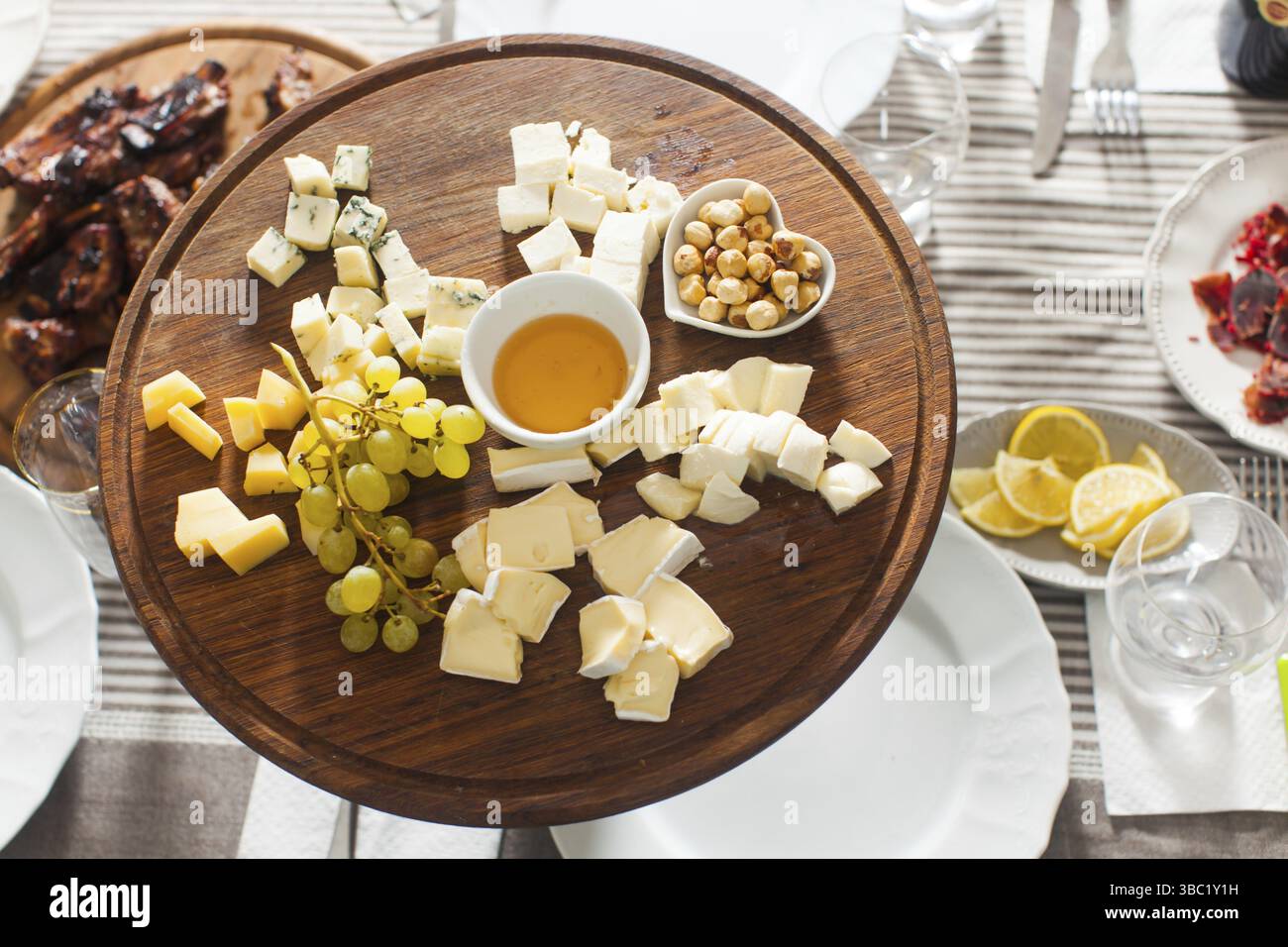 Il piatto di formaggi con nocciole, miele, uva sulla tavola di legno sul tavolo serviti Foto Stock