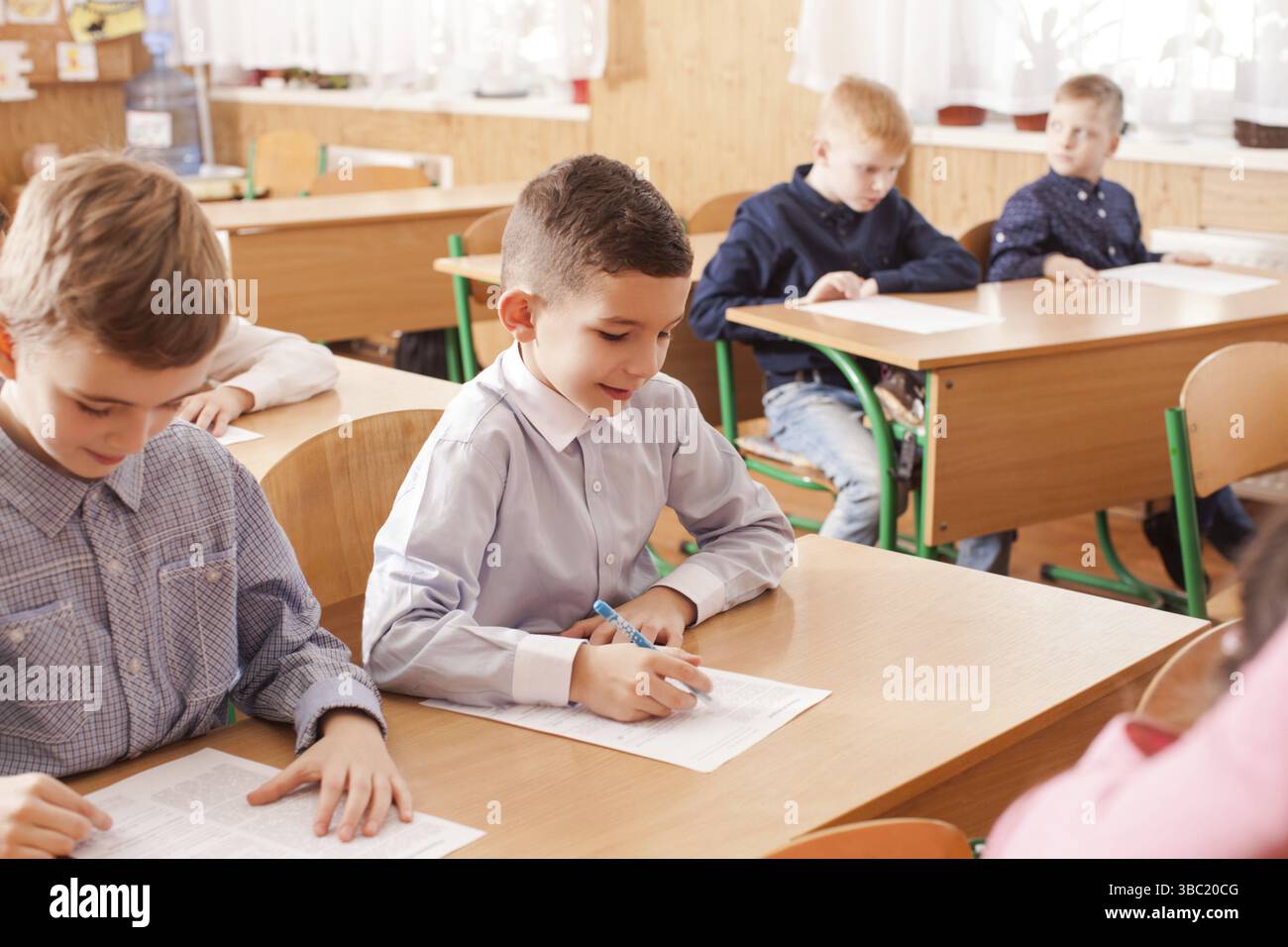 I bambini della scuola primaria che prendono un test della scuola di scrittura dell'esame Foto Stock
