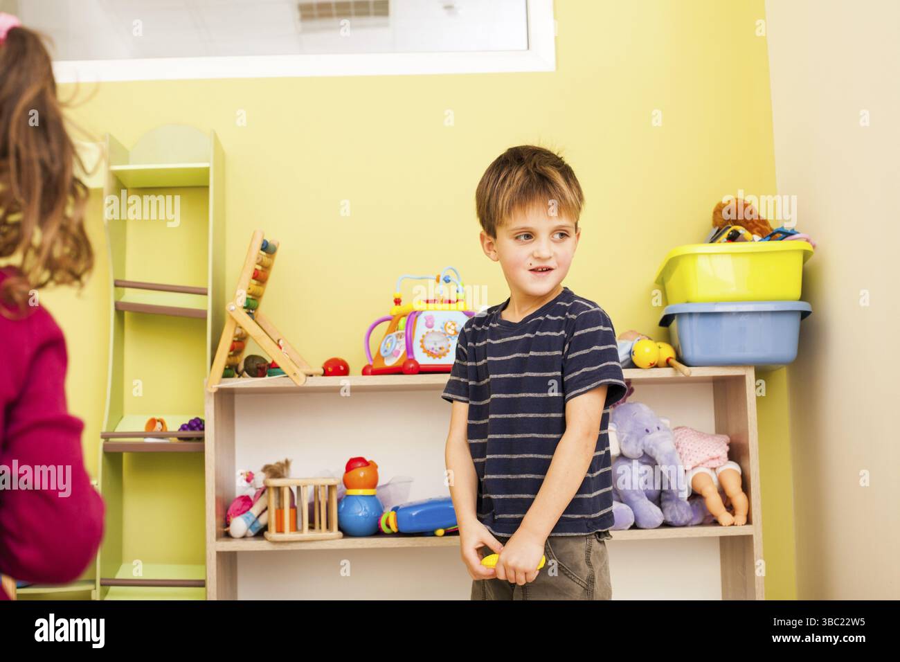 Sistemare i giocattoli e insegnare ai bambini a pulire nella sala giochi Foto Stock