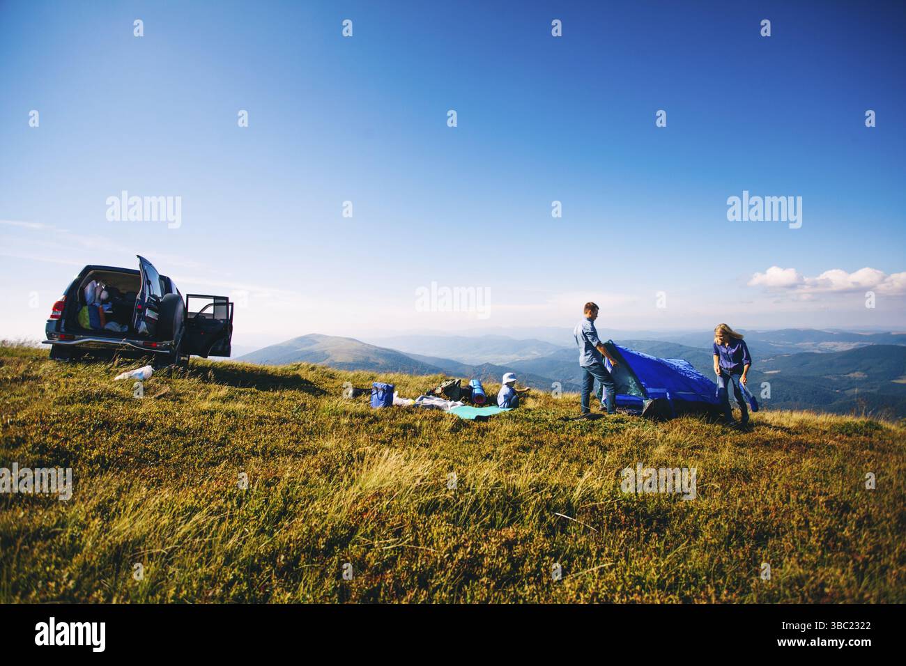 Giovane famiglia viaggi in auto. Rilassante e preparare la tenda in vacanza in campeggio Foto Stock