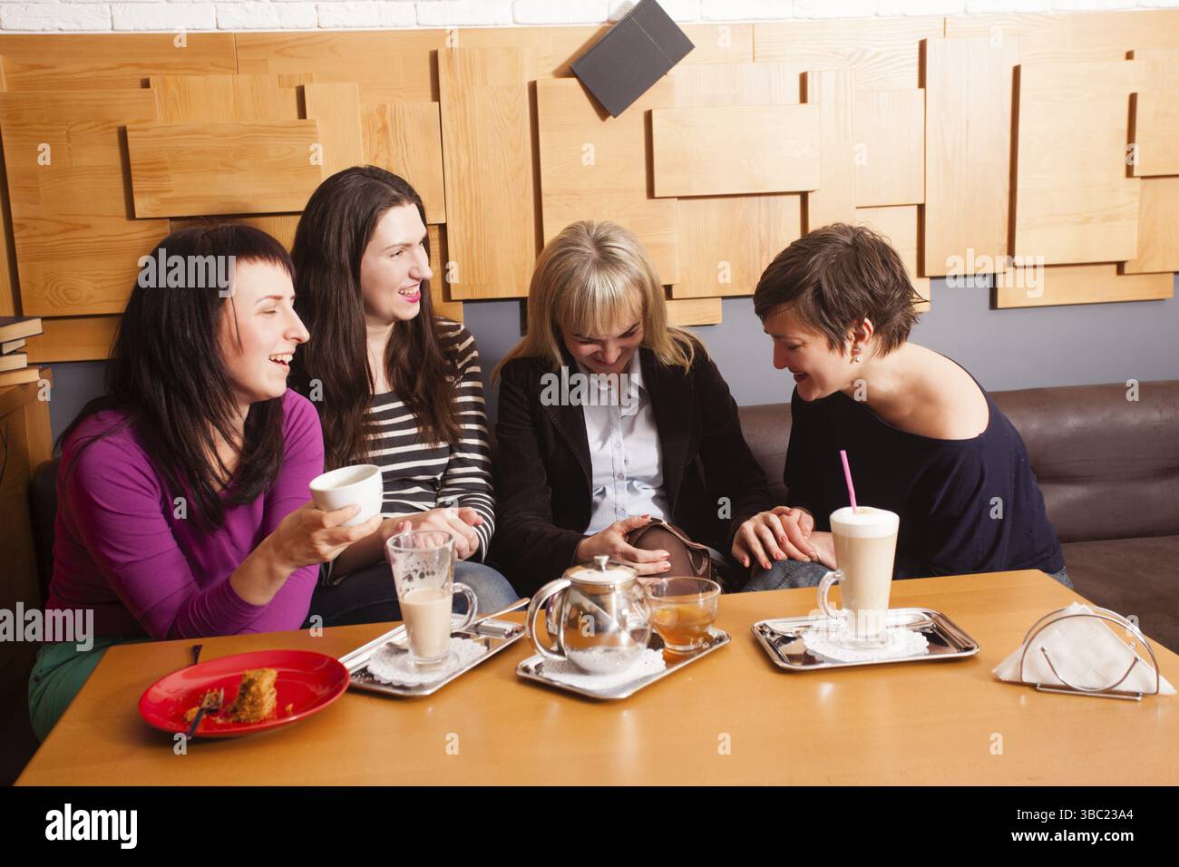 Amiche a discutere le ultime notizie durante la riunione informale nella caffetteria Foto Stock