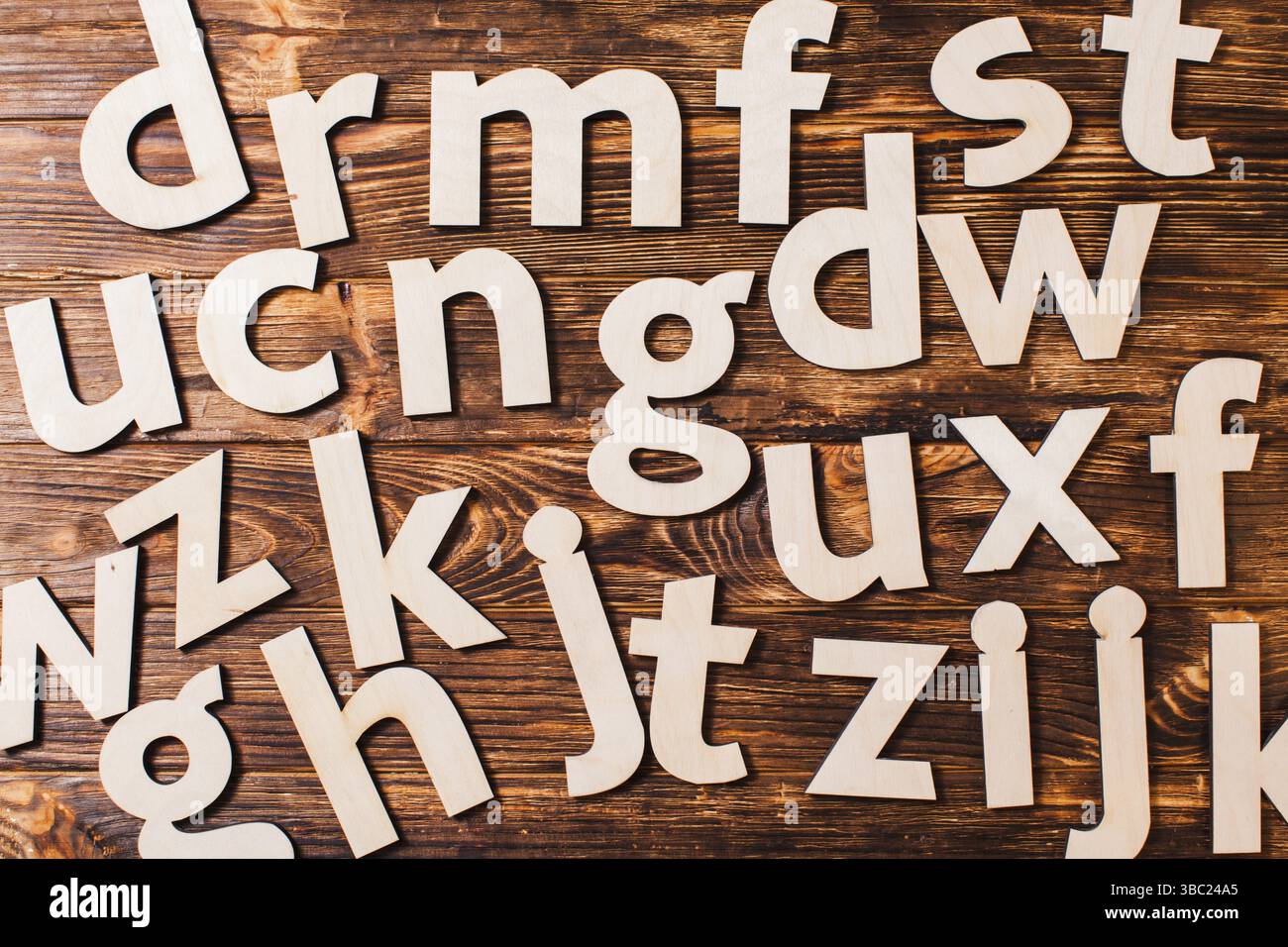 Le grandi lettere dell'alfabeto sono sparse caoticamente su fondo di legno. Concetto di educazione Foto Stock