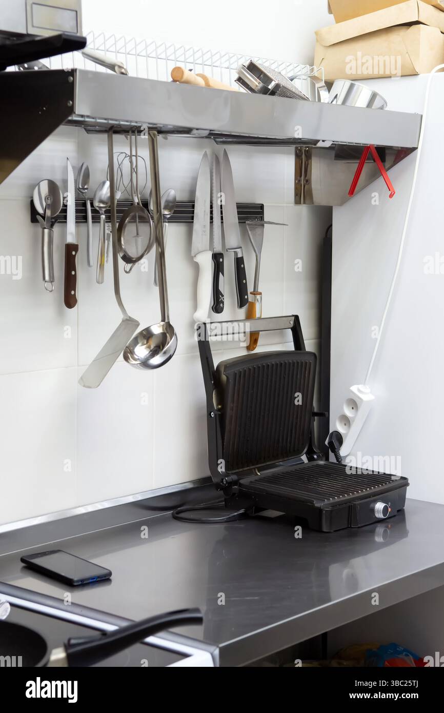 Strumenti da cucina professionali appesi sopra un piano di lavoro nero Foto Stock