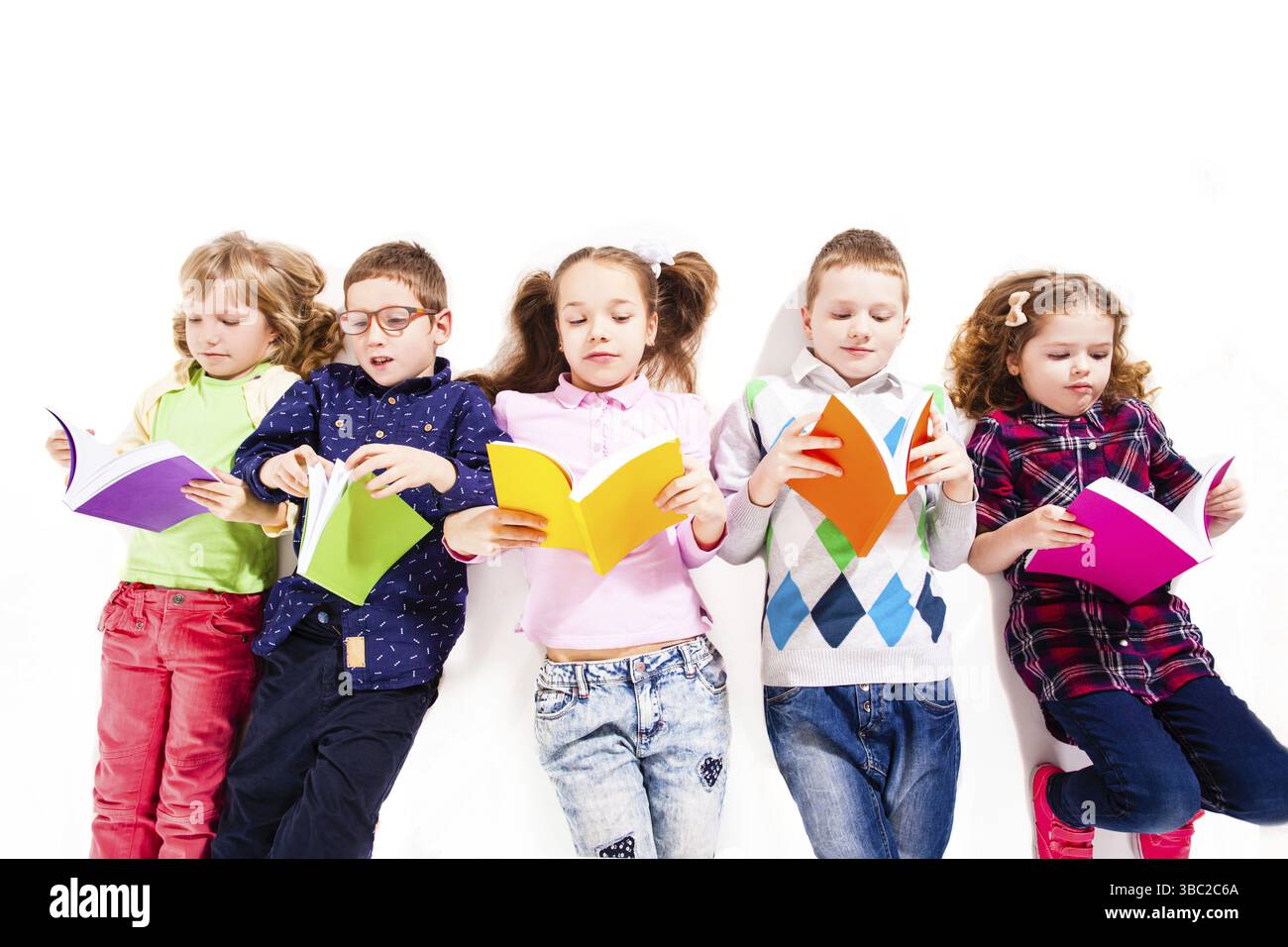 I bambini con i libri sono sdraiati sul pavimento e leggono. Concetto di istruzione e abilità, isolato sullo sfondo bianco Foto Stock