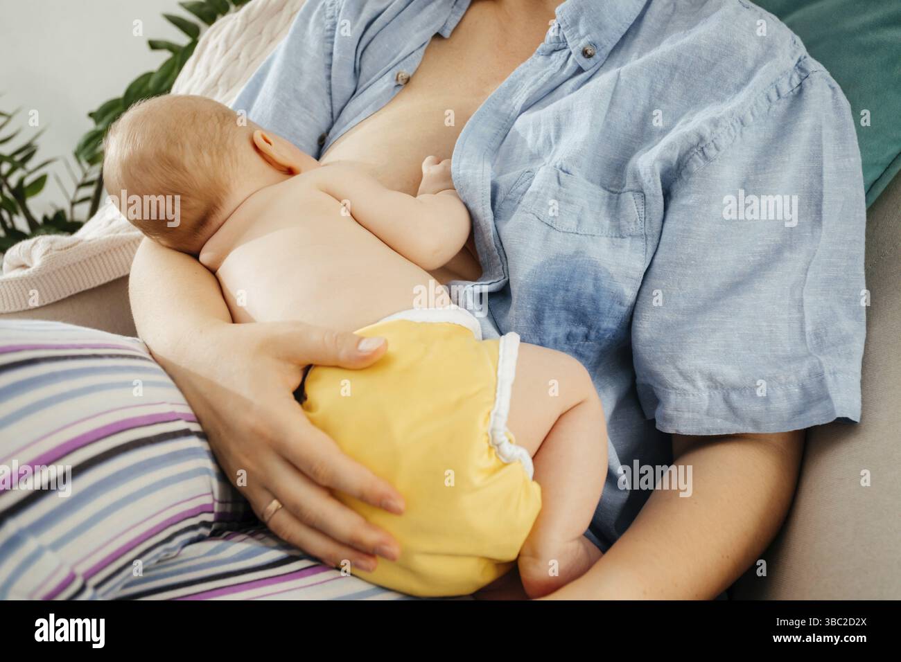 La giovane e bella madre seduta su una comoda sedia e che ha un tempo tranquillo per legarsi con il suo bambino Foto Stock